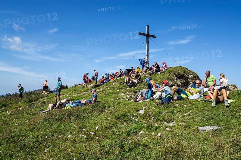 Mountain hikers rest at the summit cross of the Hoher Ifen mountain