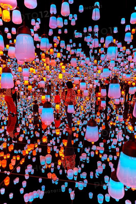 Visitors in the middle of a light installation with brightly lit lamps