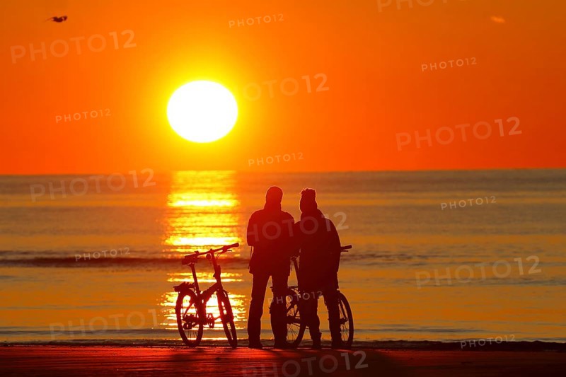 Couples with bikes on the beach watching the sunset