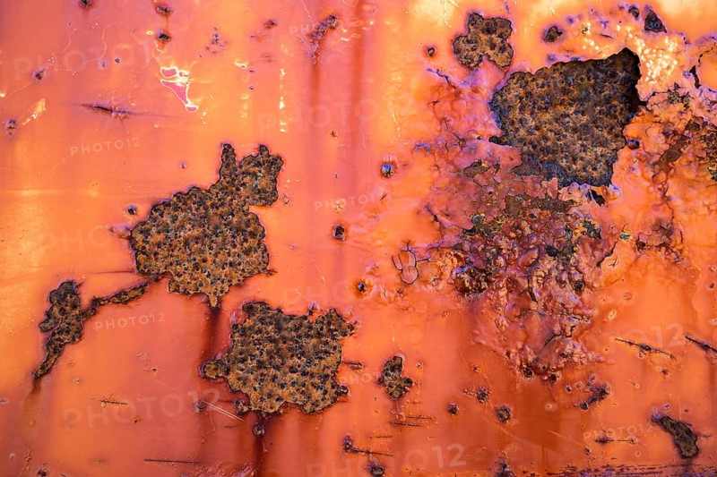 Peeling paint and rust on orange metal wall