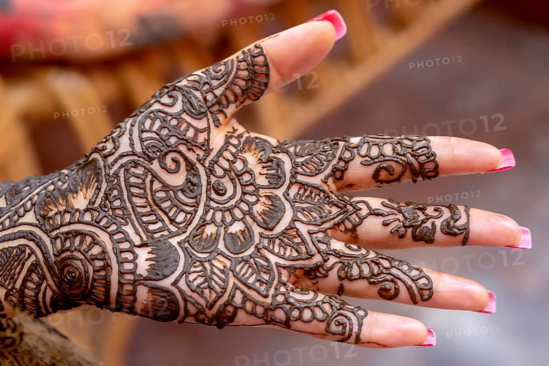 Mehendi tatooed hand of Indian bride on her wedding eve