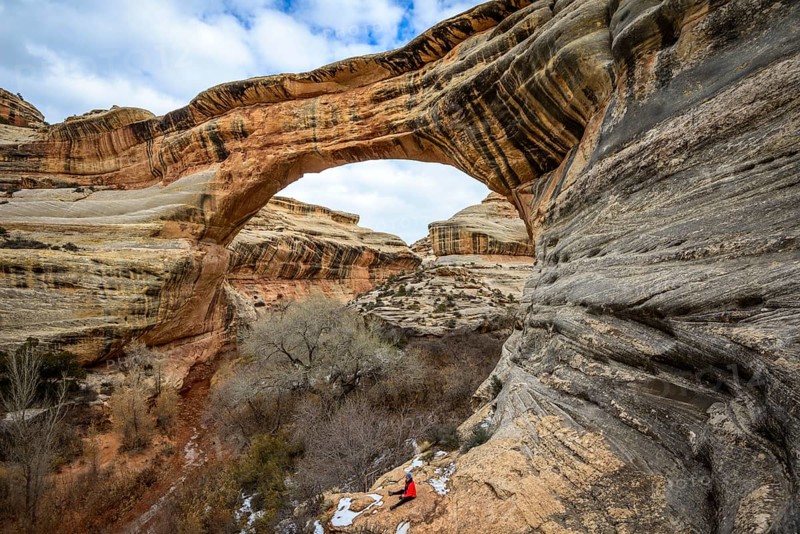 Tourist sits under rock arch