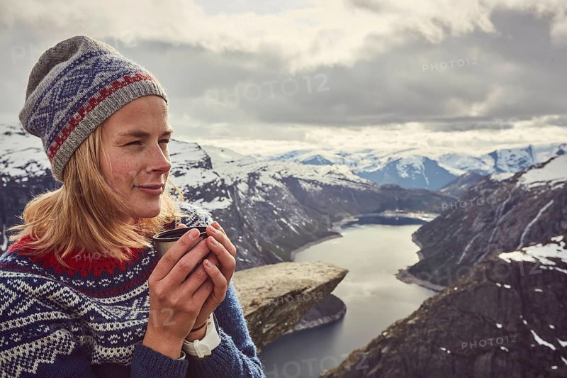 Young woman in Norwegian sweater drinks tea