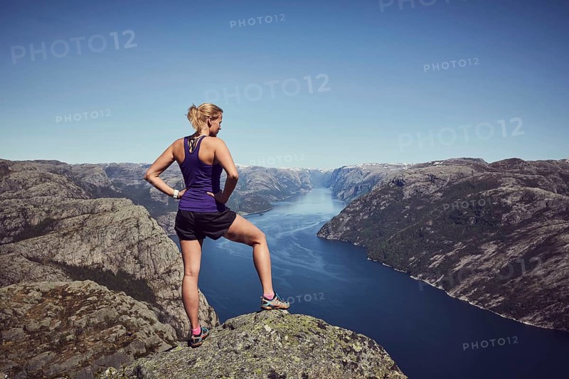 Young woman enjoying the view over the fjord from the top of Preikestolen