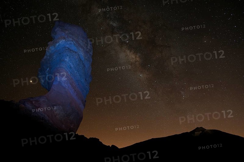 Illuminated Roque Cinchado and Pico del Teide with starry sky