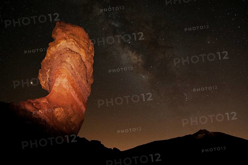 Illuminated Roque Cinchado and Pico del Teide with starry sky