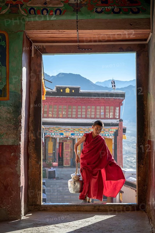 Young monk bringing butter milk tea to the prayer hall