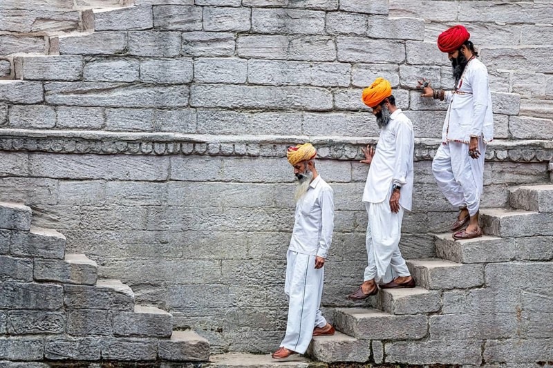 Three men walking down the steps at the stepwell Toorji Ka Jhalra in Jodhpur