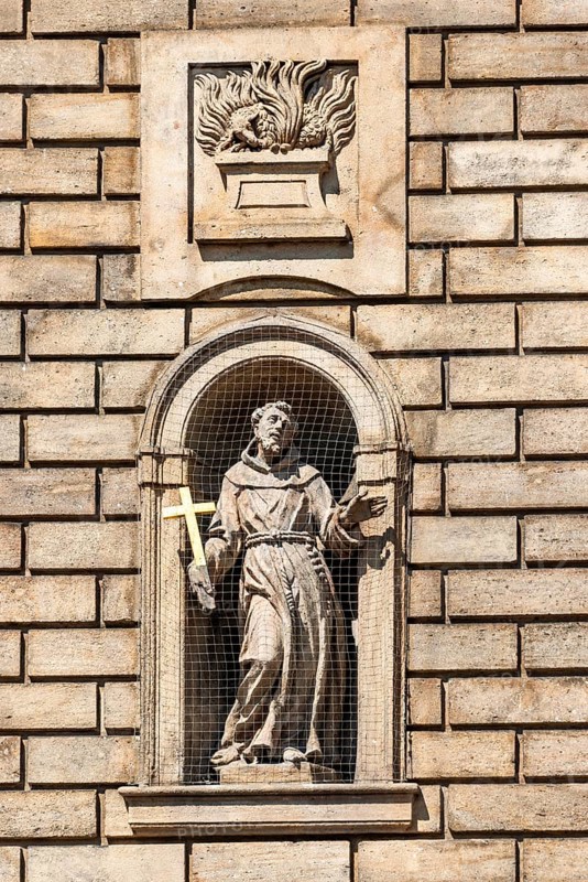 Statue of St. Francis of Assisi in a niche on the facade of the Church of the Knights of the Cross