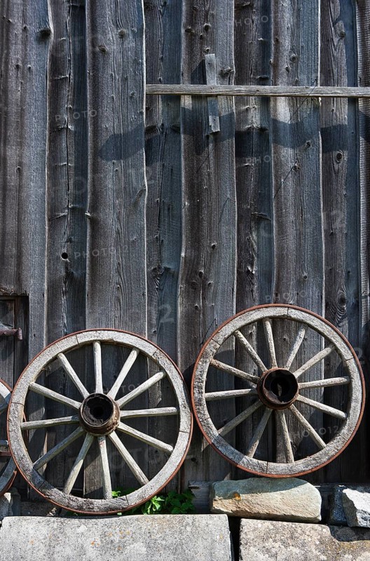 Two old wagon wheels in front of a barn