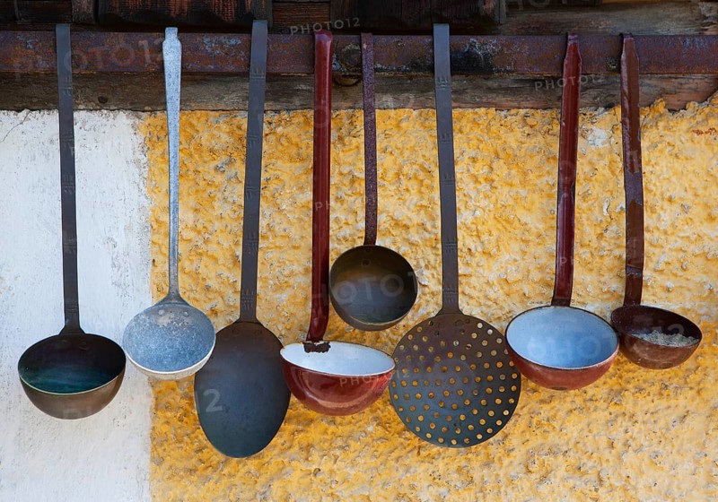 Various ladles hanging on a wall of a farm