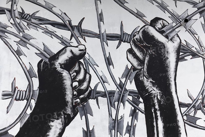 Hands pull barbed wire apart