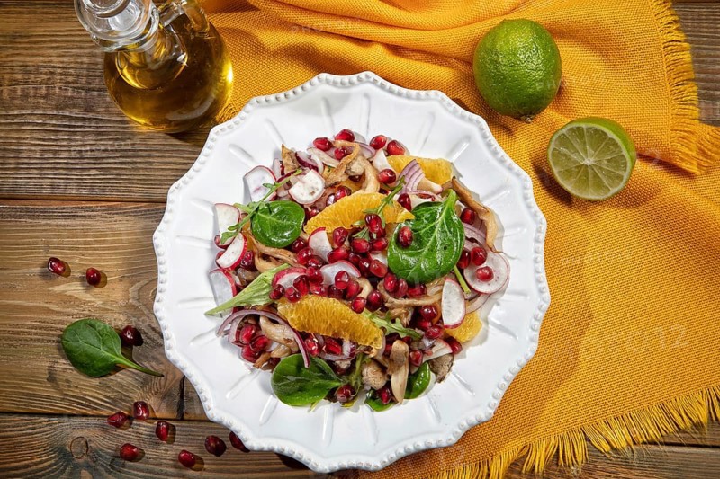 Served salad on a porcelain plate with orange slices