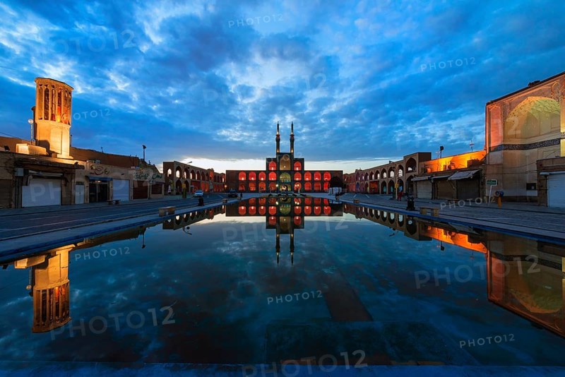 Amir Chaqmaq complex facade illuminated at sunrise and reflecting in a pond