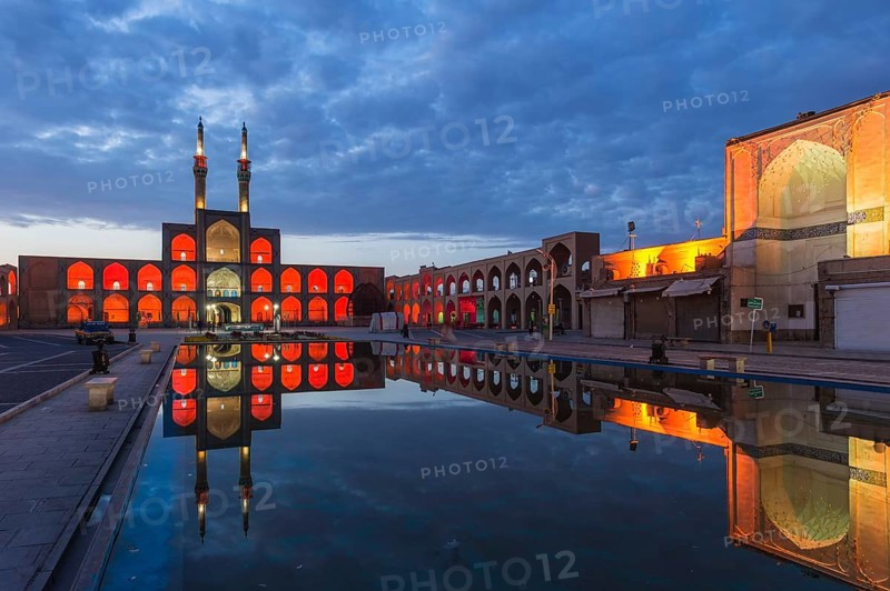 Amir Chaqmaq complex facade illuminated at sunrise and reflecting in a pond