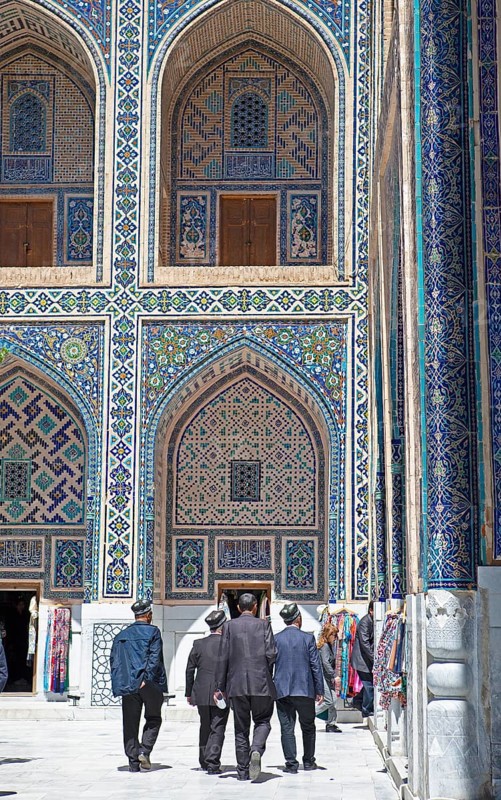 Men with Doeppi in the courtyard with pointed arch niches of the Ulug'Bek-Medrese