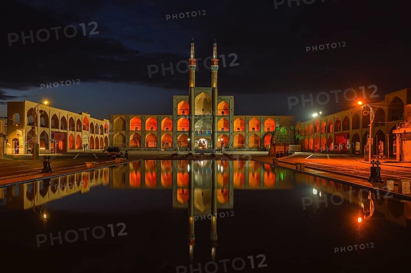 Amir Chaqmaq complex facade illuminated at sunrise and reflecting in a pond