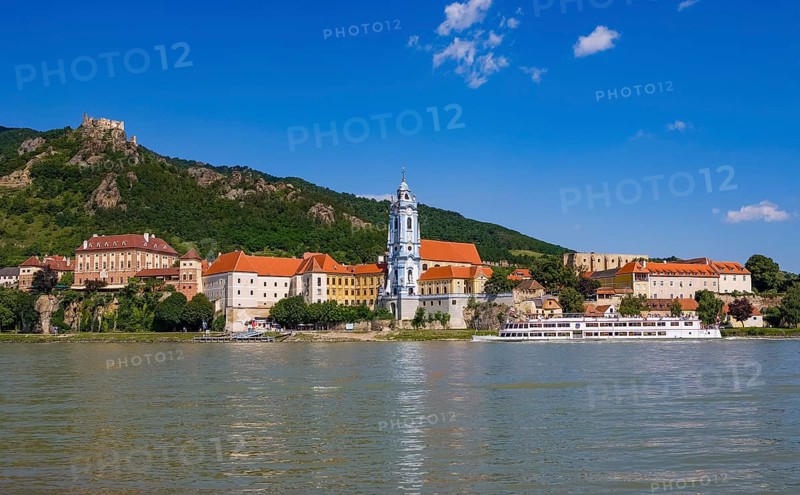 Excursion boat on the Danube in front of the baroque church of Duernstein Abbey