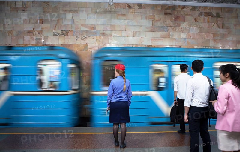 Conductor in uniform and passengers waiting at the passing train