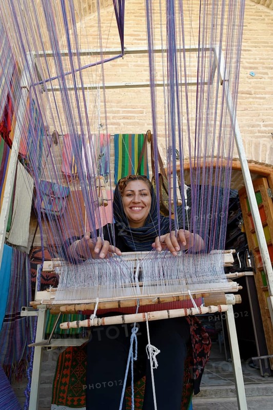 Iranian woman weaving a carpet