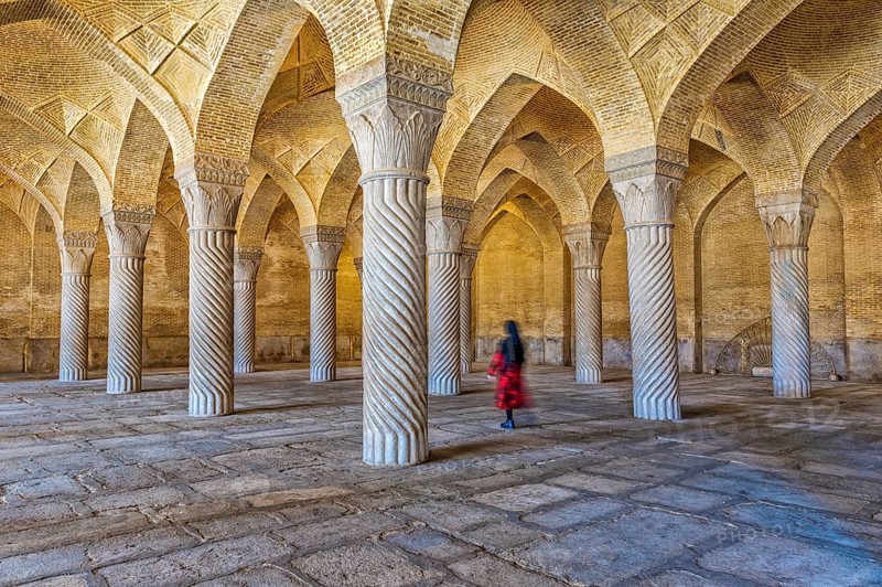 Iranian woman walking through the prayer hall with Shabestan pillars