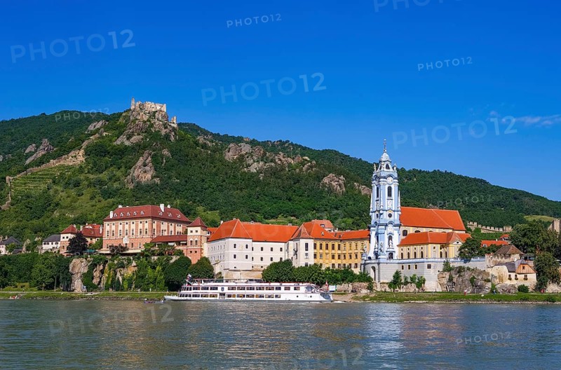 Excursion boat on the Danube in front of the baroque church of Duernstein Abbey