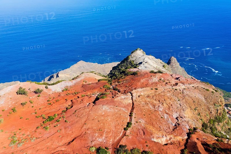 Eroded mountain slope with red earth at the coast