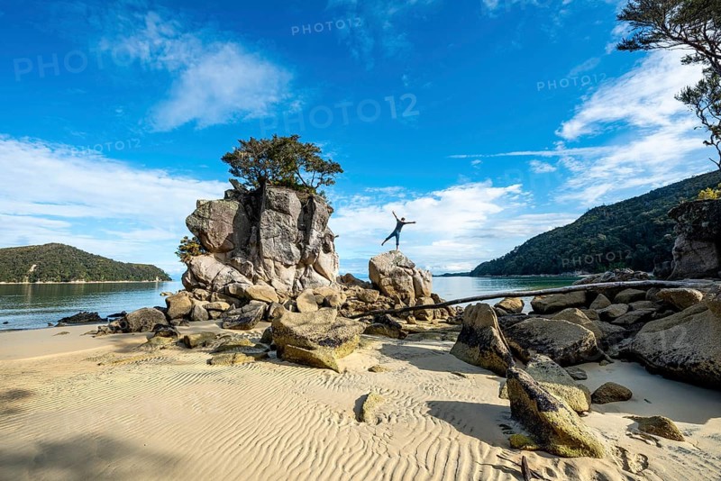 Young man standing with outstretched arms on a rock