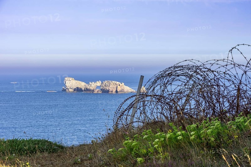 Barbed wire and view of small island in the sea