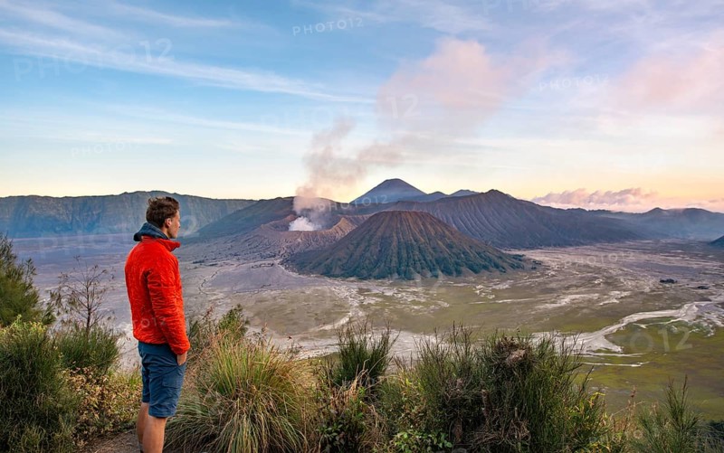 Young man in front of volcanic landscape at sunset