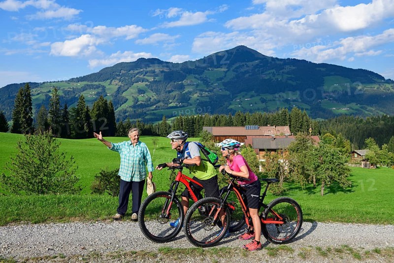 Old farmer's wife shows two cyclists with electric mountain bikes