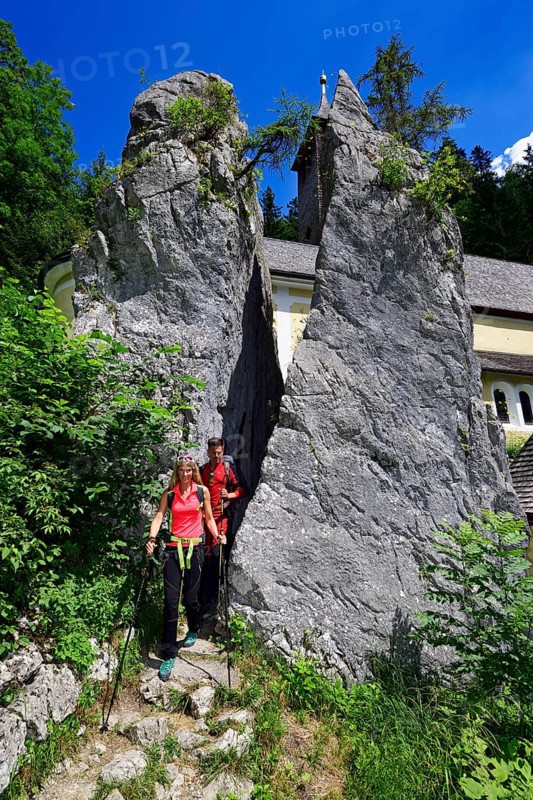 Hikers walk through the split rock at Klobenstein