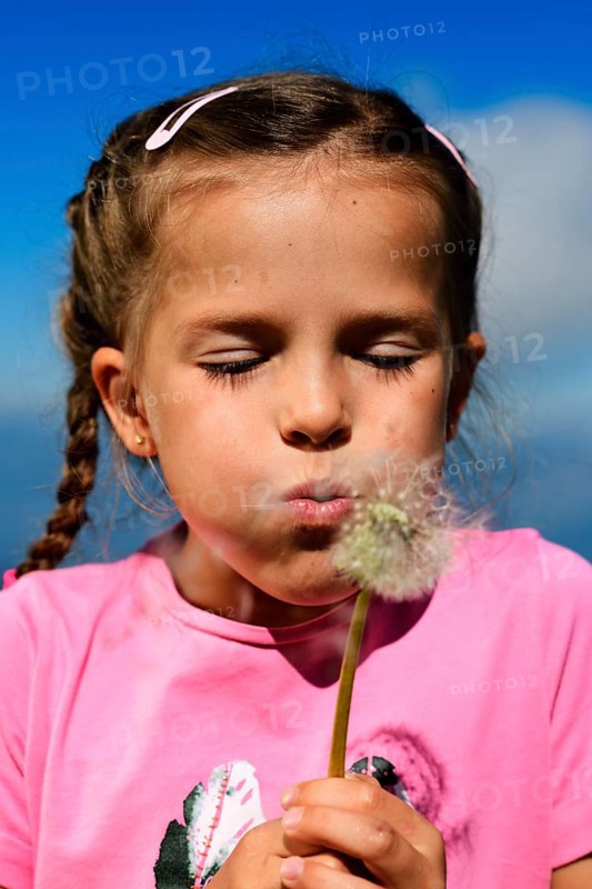 Girl blowing in dandelion