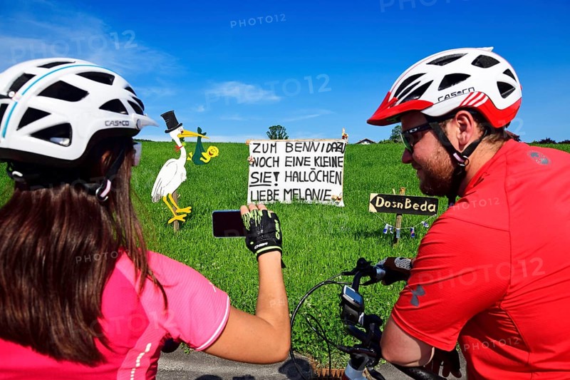 Cyclists photographing Rattling stork and banner as a welcome for a newborn child
