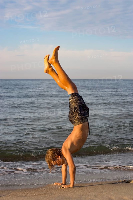 Youth doing a handstand at the Baltic Sea beach