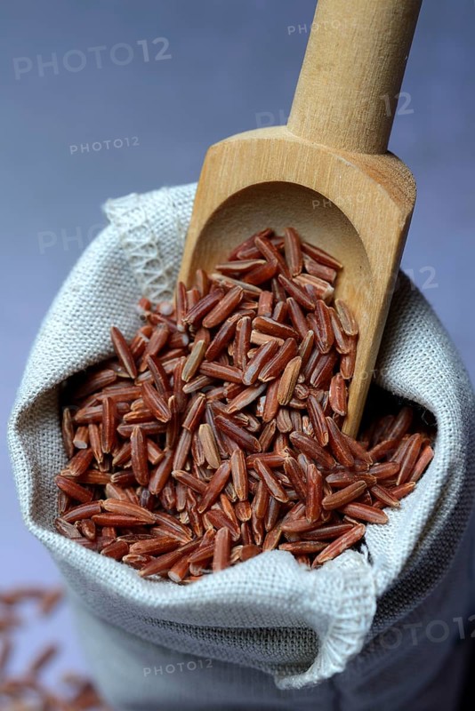 Red rice in bag with wooden shovel