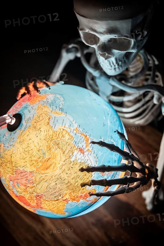 Skeleton with bony hand on globe