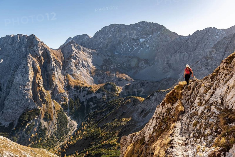 Mountaineer with climbing helmet running on a steep mountain slope
