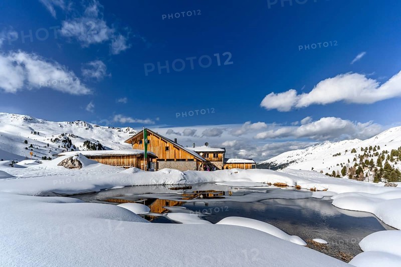 Snowy Lizumer Hut with small mountain lake in winter