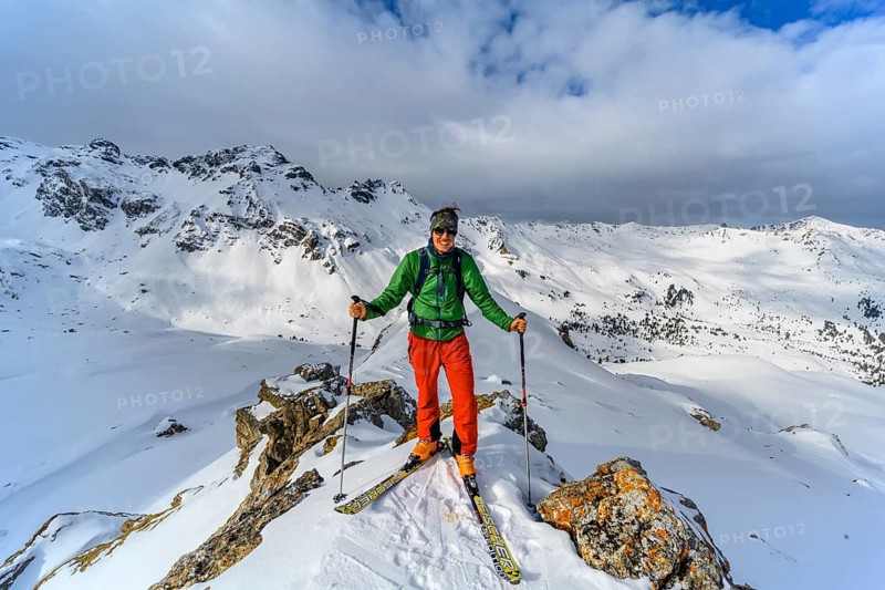Ski tourers in front of a snow-covered mountain landscape