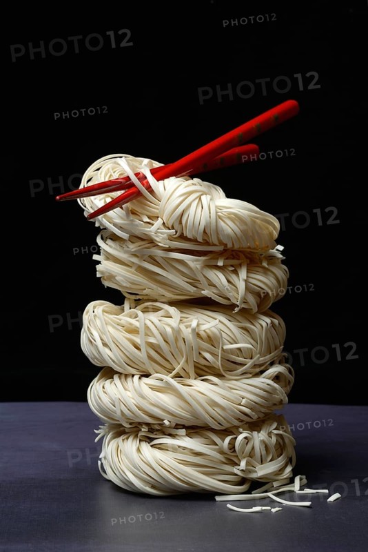 Stacked Asian nest noodles and red chopsticks