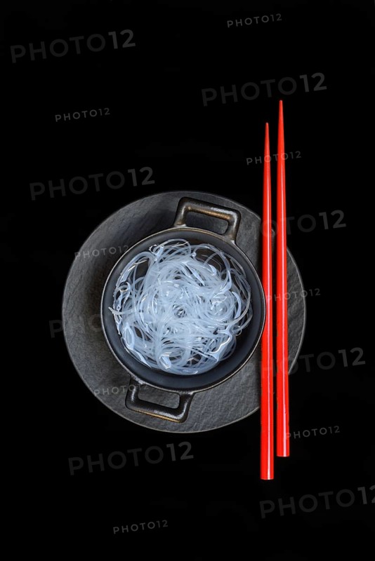 Asian glass noodles in pot and red chopsticks