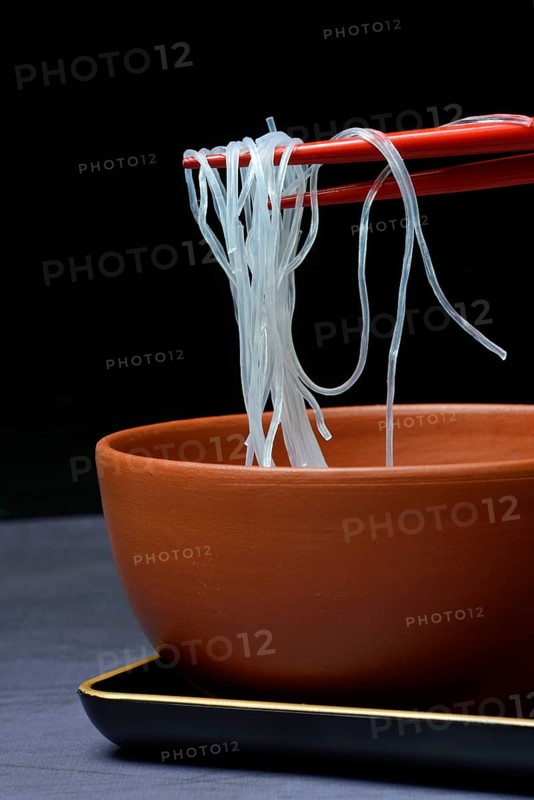 Asian glass noodles on chopsticks over bowl