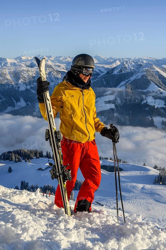 Skier stands at the ski slope and holds ski
