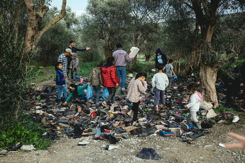 Refugees look for shoes from a pile of donations