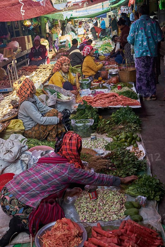Market woman offer vegetables and sit on the floor