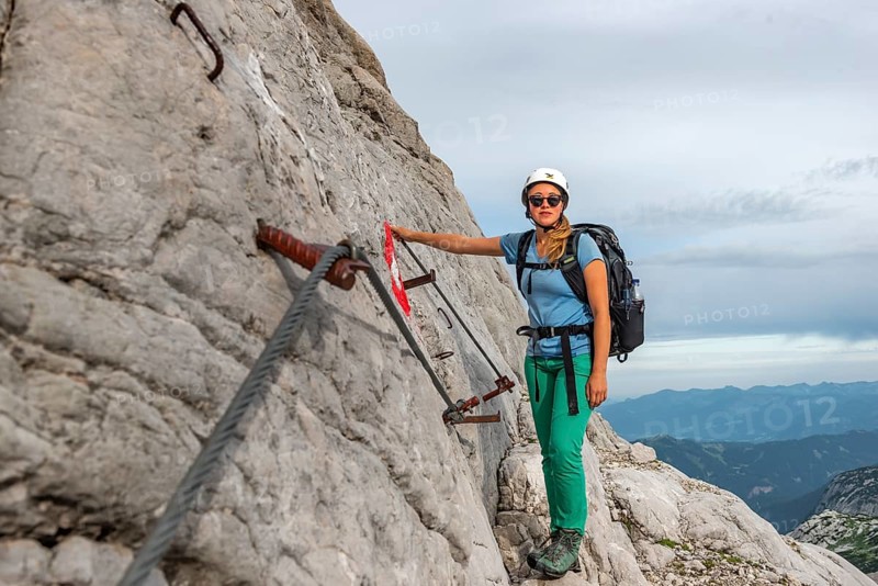 Mountaineer on secured route on steep rock face
