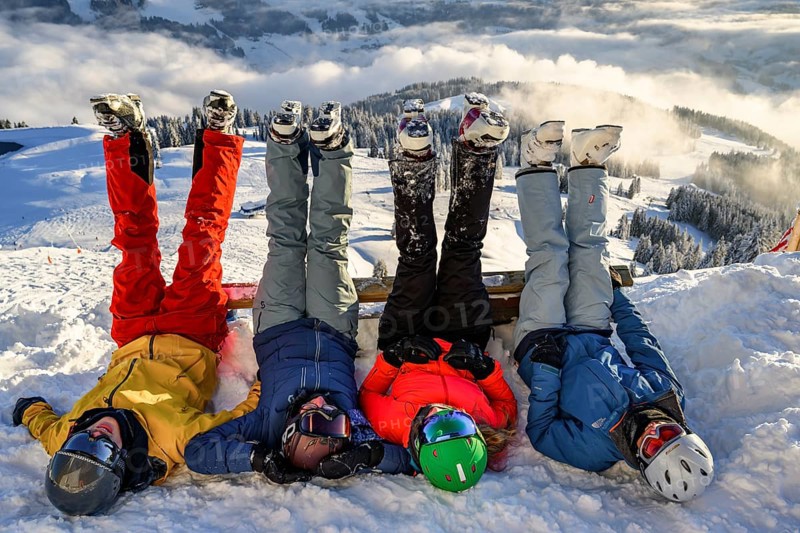 Skiers lie in the snow and stretch their legs in the air