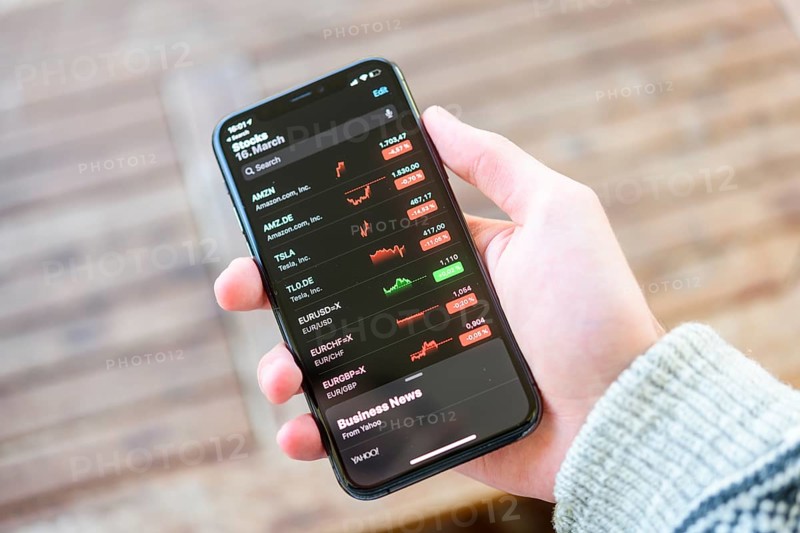 Hand holds iPhone 11 with stock app on display