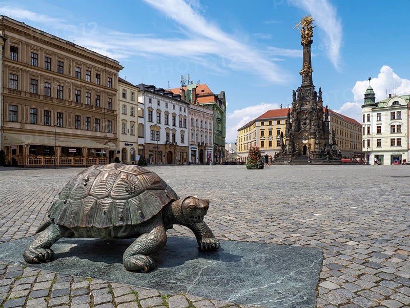 Sculpture of a turtle on the Oberring square with Unesco World Heritage Column of the Trinity